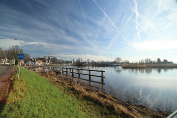 Oude Veerstal along the quay of river Hollandsche IJssel with windmill 't Slot in Gouda, the Netherlands