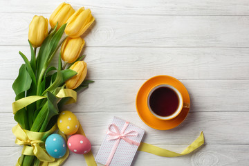 Easter greeting card with tulip flowers bouquet and easter eggs. Top view over white wooden table with space for your greetings