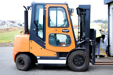 Fototapeta na wymiar Reliable loader, forklift truck. A worker is ready to load pallets with a mini loader