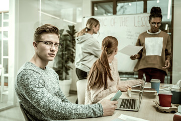 Handsome blonde-haired student wearing glasses sitting at the table