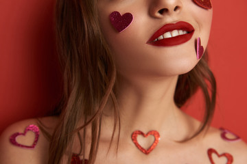 Cropped photo of brunette girl decorated with heart-shaped stickers indoors