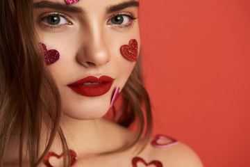 Pretty naked brunette girl is decorated with heart-shaped stickers indoors