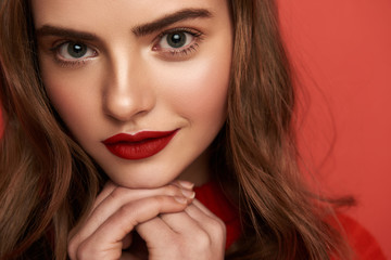 Fototapeta premium Beautiful portrait of young lady looking at camera on red background