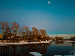 Rural river. Melting of the river in the spring. Ice and moon on the river at night.
