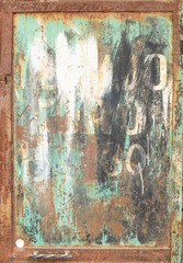 Rusted green, white and black metal panel with white letters