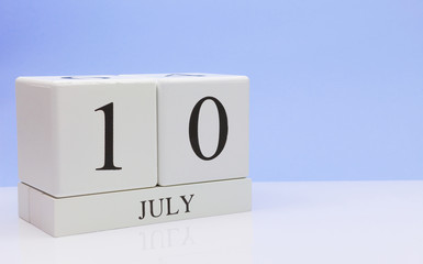 July 10st. Day 10 of month, daily calendar on white table with reflection, with light blue background. Summer time, empty space for text