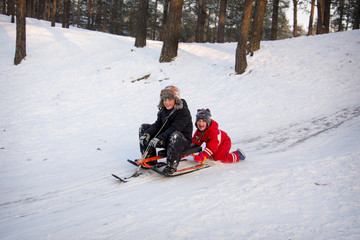 Fototapeta na wymiar In winter, children ride a snow scooter from a hill.
