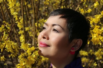 femme asiatique devant un Forsythia en fleur