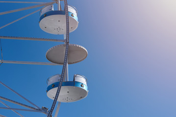 Ferris wheel in amusement park against clear blue sky. Close view.