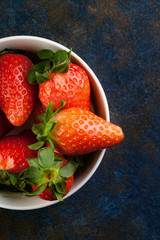VISTA CENITAL DE FRESAS ROJAS EN BOL SOBRE FONDO GRIS AZUL CON TEXTURA