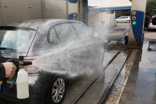 Man Spraying Active Foam During Car Wahing on Blurred Backgorund