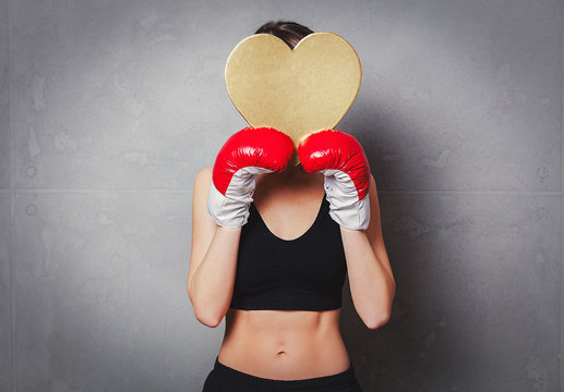 woman in boxing gloves with heart shape gift box in hands