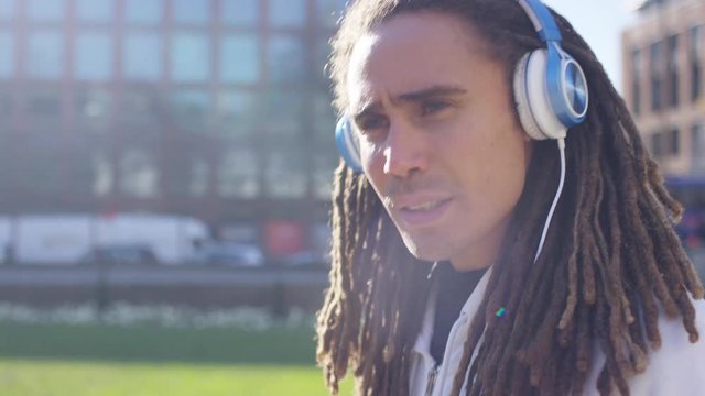 Profile portrait of man with headphones walking through the city enjoying his music