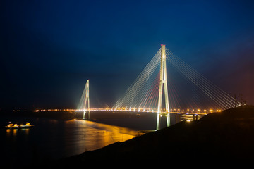 Fototapeta na wymiar Amazing zooming out aerial view of the Russky Bridge, the world's longest cable-stayed bridge, and the Russky (Russian) Island in Peter the Great Gulf in the Sea of Japan. Sunrise. Vladivostok, Russia