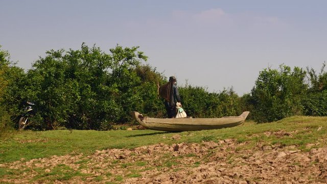 Fisher carrying his push basket and his plastic bag filled with clams through a field 