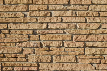Very rugged tan color stone brick wall background