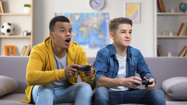 Emotional European and Afro-American friends playing video games, leisure time
