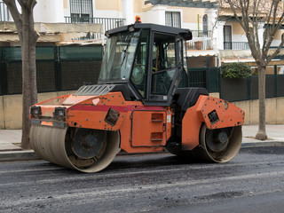Rodillo de asfalto pesado moderno que apila y presiona asfalto caliente. Máquina de reparación de camino naranja. Reparación en ciudad moderna con máquina de rodillo de vibración. 
