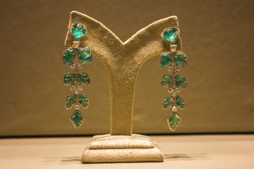 turquoise earrings ,pair of long ones with white stones displayed in a velvet stand with a beige velvety background
