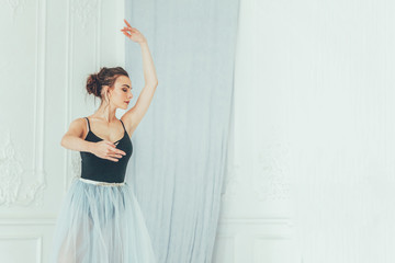 Young classical ballet dancer woman in dance class. Beautiful graceful ballerina practice ballet positions in blue tutu skirt near large mirror in white light hall