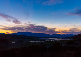 Vivid blue and peach sunset sky with clouds and mountains over a partially dry lakebed at Yuba State Park, Utah