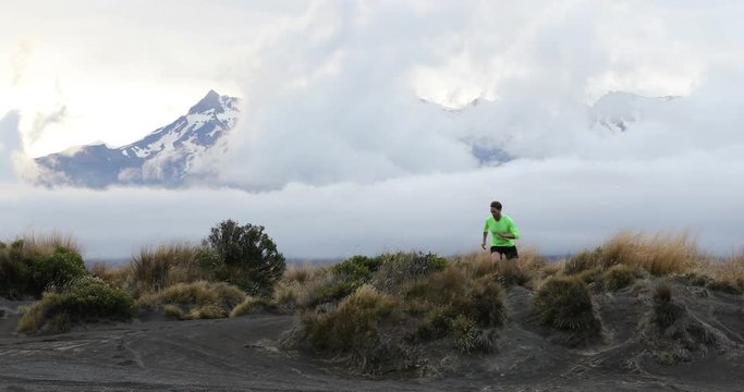 Trail runner man running in New Zealand mountains nature. Sport athlete jumping over hills near tongariro national park at dusk landscape background. Active health and motivation lifestyle. 59.94 FPS