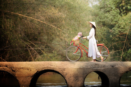 woman with Vietnam culture traditional dress, Ao dai and bicycle on the bridge