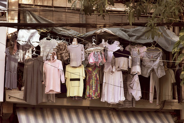 Clothes of different colors weigh on hangers at a street shop, open second-hand showcase