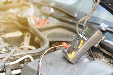 close up electronic multi meter device or tool during use for electric system check of car repair on automobile gasoline or diesel engine at garage