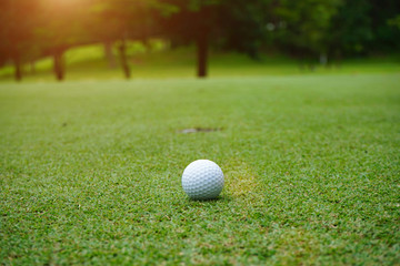 golf ball in beautiful golf course with sunset. Golf ball close up in golf coures at Thailand