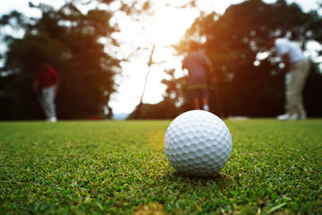 Golf ball and golf club in beautiful golf course at sunset background.