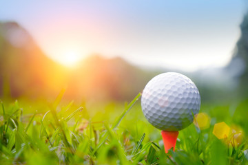 golf ball on tee in beautiful golf course with sunset. Golf ball close up in golf coures at Thailand