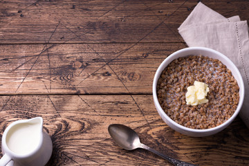 Fototapeta na wymiar Buckwheat porridge with milk and butter on a wooden table