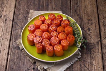 Delicious baked carrots with spices and thyme on a wooden table