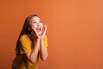 Young Asian woman portrait over orange background announce shot, smile happy studio shot © Nattakorn