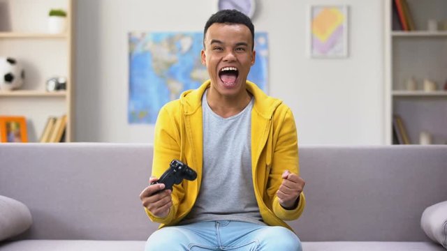 Game addicted Afro-American teenage boy winning computer game, procrastination