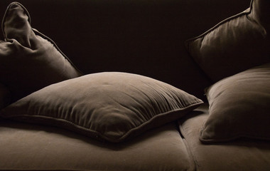 Brawn scattered cushions on a brown couch moody setting image with copy space in landscape format