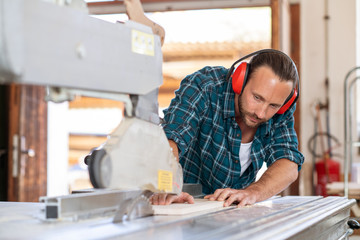 young worker in a carpenter's workshop working with saw
