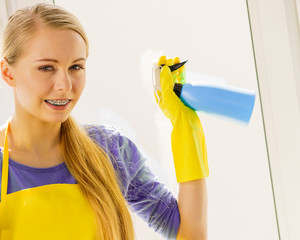 Girl cleaning window at home