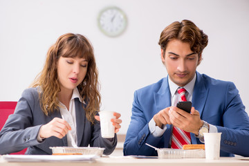 Two colleagues having lunch break at workplace
