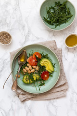 Vegan salad with rucola, seeds, avocado, orange and beans seasoned with olive oil. Healthy eating concept