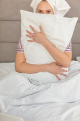 Young beautiful girl hugging pillow while sitting in the bed at home, free time, spare time. close up photo, lifestyle