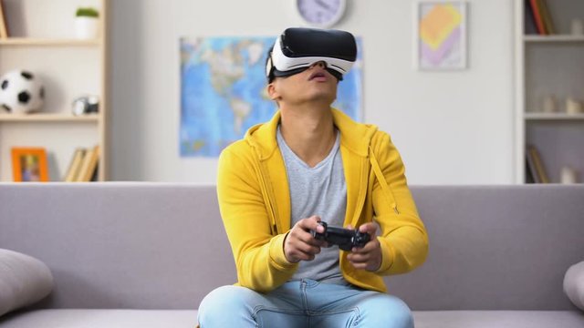 Emotional African-American guy in VHR playing video game, reality simulation