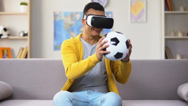 Young Afro-American y in VR headset saving goal, pretending to be goalkeeper