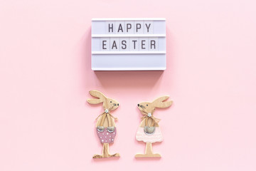 Lightbox text Happy Easter and pair of wooden bunnies on pink paper background. Concept Easter Creative top-down composition Flat lay Greeting card