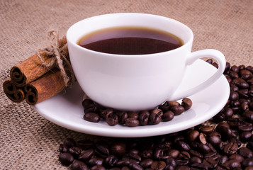 Coffee in a white cup with coffee beans and cinnamon stick