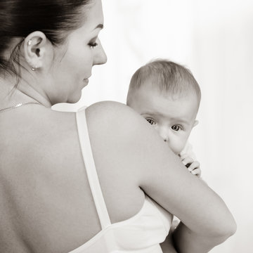 Portrait of young loving mother holding her newborn child, black white image with bit toning