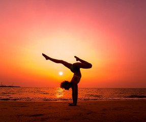 Fototapeta na wymiar Beautiful young woman practic yoga at the beach. Early morning exercise. Sunrise
