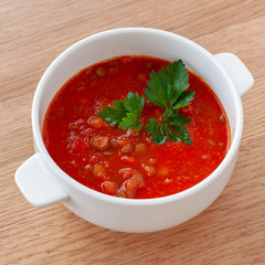 Tomato-lentil soup, decorated with herbs. Ingredients: tomatoes in their own juice, lentils, onions, spices. Square format.