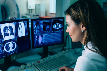 Radiologist reading a CT scan. Female doctor running CT scan from control room at hospital - obrazy, fototapety, plakaty